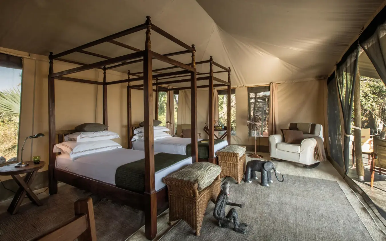 Luxury safari tent bedroom with four-poster bed and seating, Chem Chem Lodge, Lake Manyara, Tanzania
