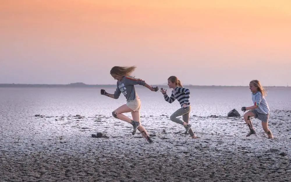 Children running together on beach at sunset, Chem Chem Lodge, Lake Manyara, Tanzania