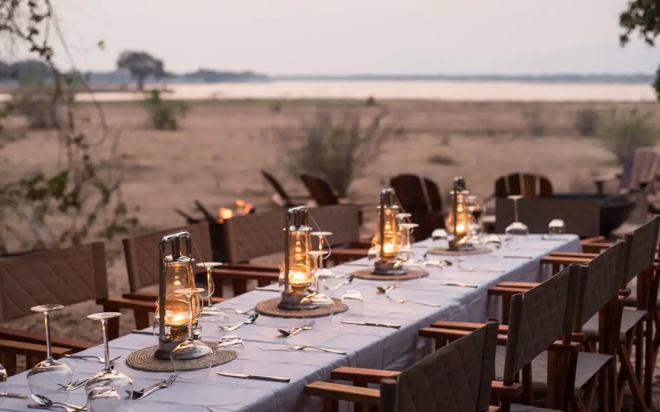 Outdoor dining table set overlooking savanna landscape at dusk, Chikwenya Camp, Mana Pools, Zimbabwe