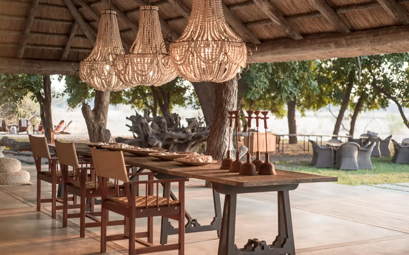 Covered dining pavilion with beaded chandeliers and wooden tables, Chikwenya Camp, Mana Pools, Zimbabwe