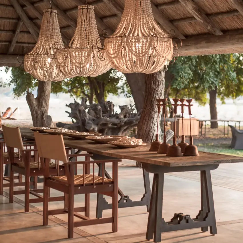 Covered dining pavilion with beaded chandeliers and wooden tables, Chikwenya Camp, Mana Pools, Zimbabwe