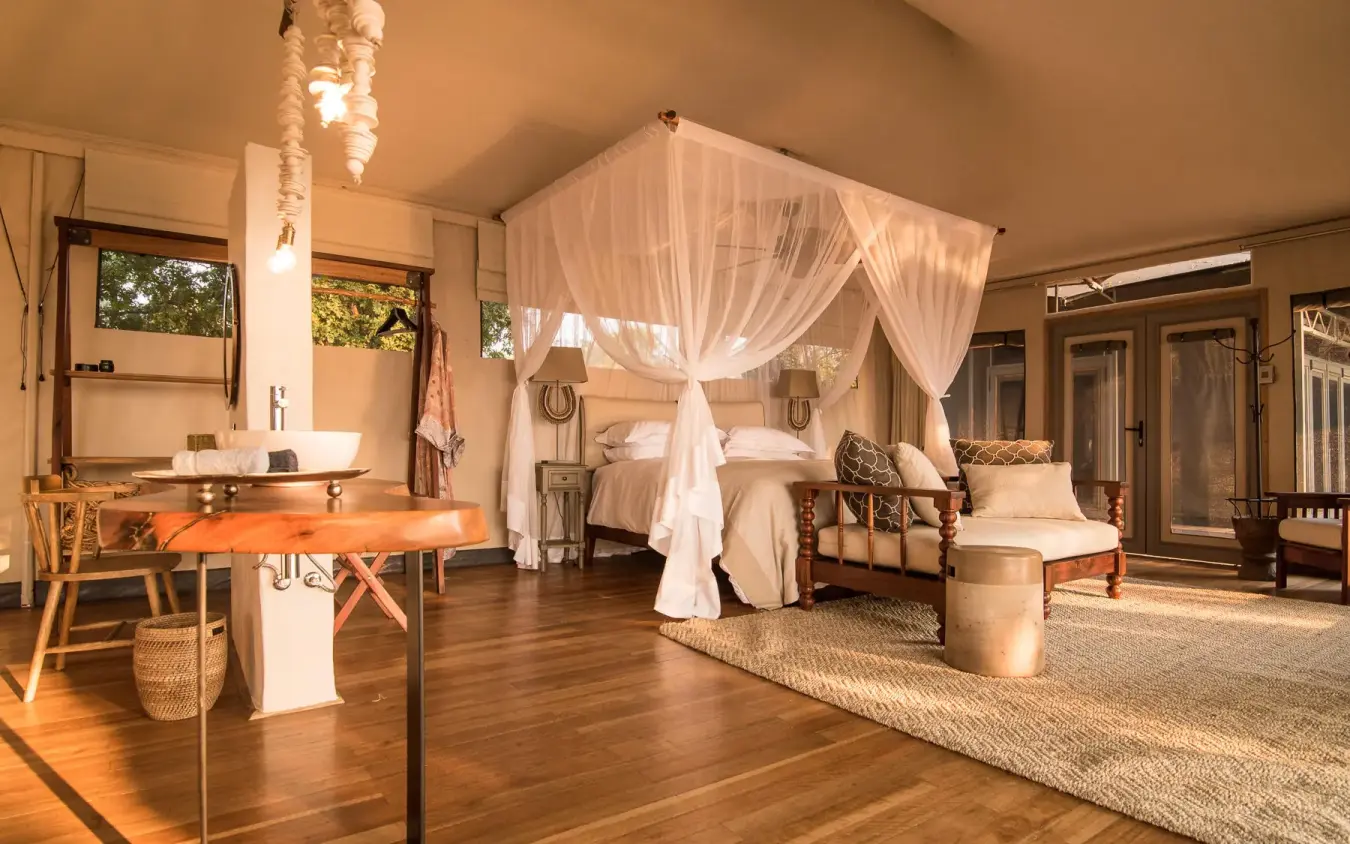 Spacious safari bedroom with canopy bed and open-air design, Chikwenya Camp, Mana Pools, Zimbabwe