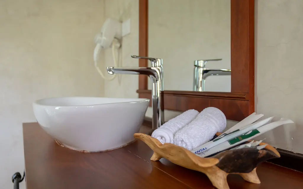 Modern bathroom sink with towels and amenities on wooden counter, Chimpundu Lodge, Kibale Forest, Uganda