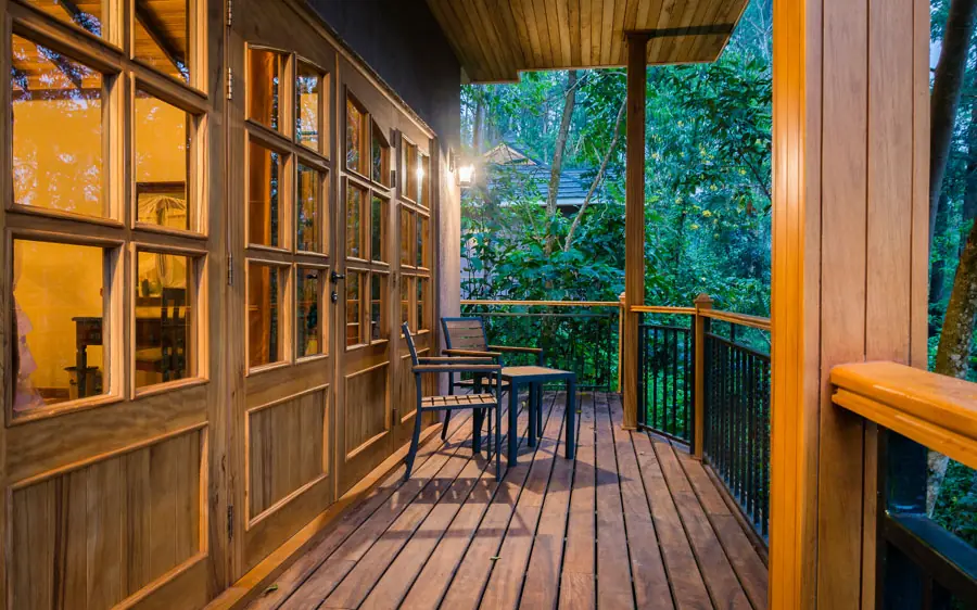 Wooden deck with dining table overlooking forested landscape at dusk, Chimpundu Lodge, Kibale Forest, Uganda