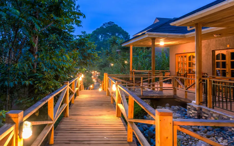 Wooden deck with railings lit at dusk overlooking forest, Chimpundu Lodge, Kibale Forest, Uganda