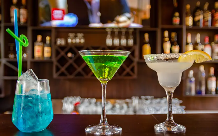 Three colorful cocktails on bar counter with bottles behind, Chimpundu Lodge, Kibale Forest, Uganda