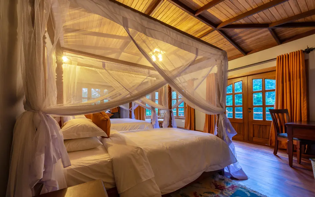 Luxurious bedroom with sheer canopy bed and wooden ceiling, Chimpundu Lodge, Kibale Forest, Uganda