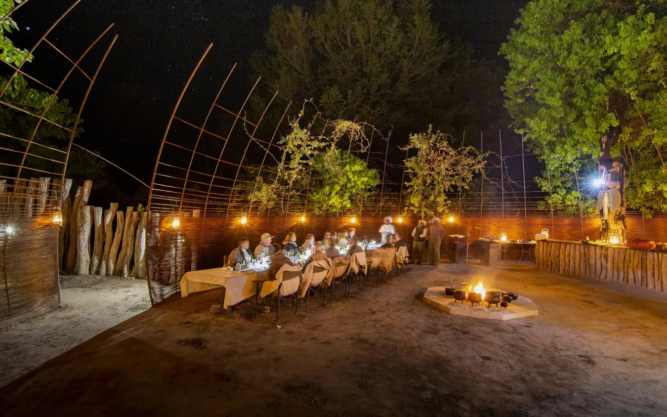 Outdoor dinner setup with firepit under starlit sky, Chitabe Camp, The Okavango Delta, Botswana