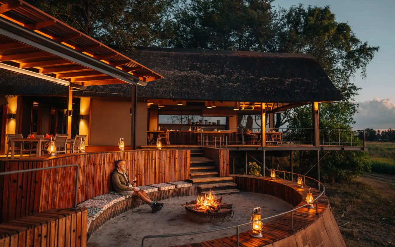 Thatched lodge with firepit at golden hour dusk, Chitabe Camp, The Okavango Delta, Botswana