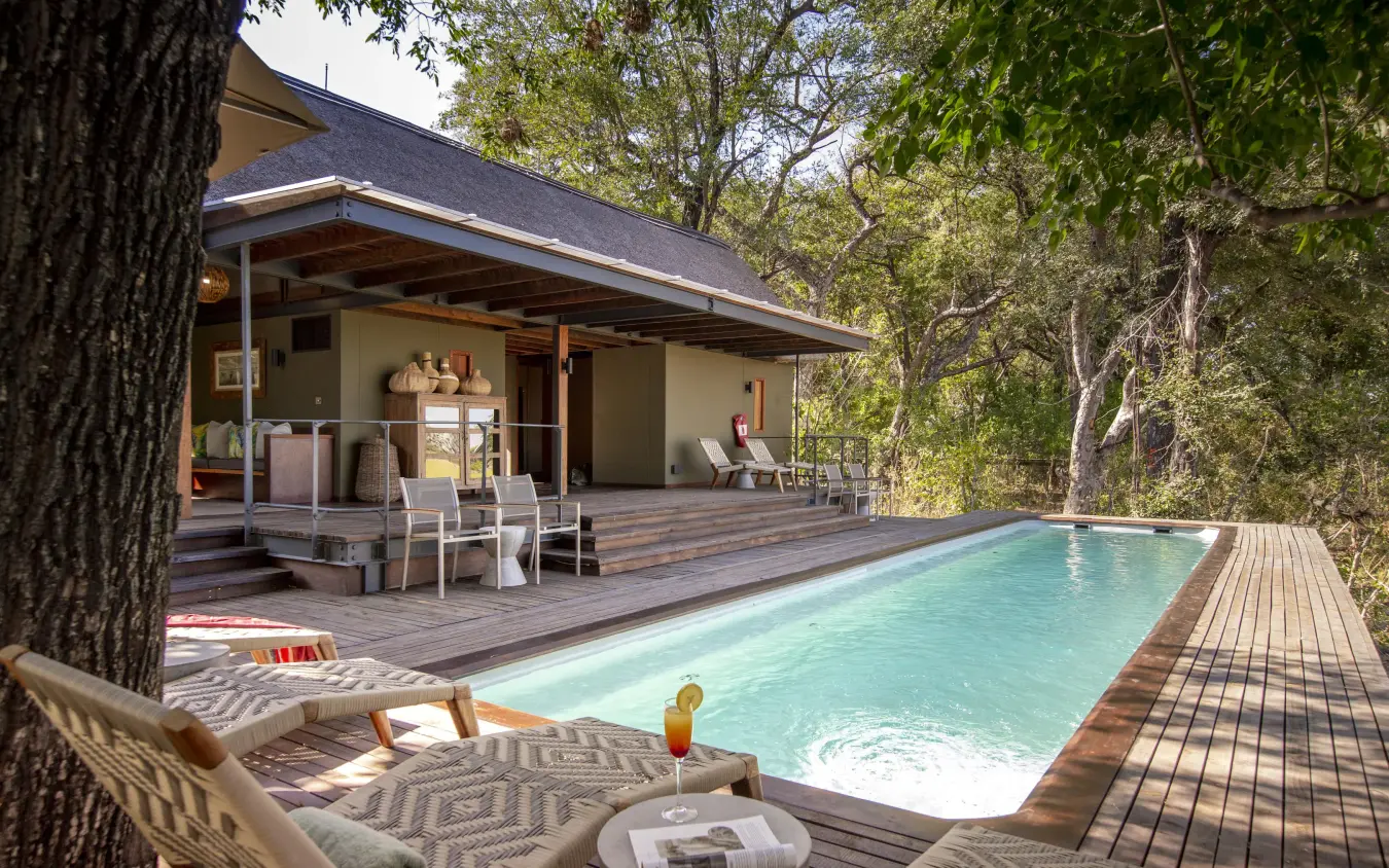 Swimming pool with wooden deck and safari lodge building, Chitabe Camp, The Okavango Delta, Botswana