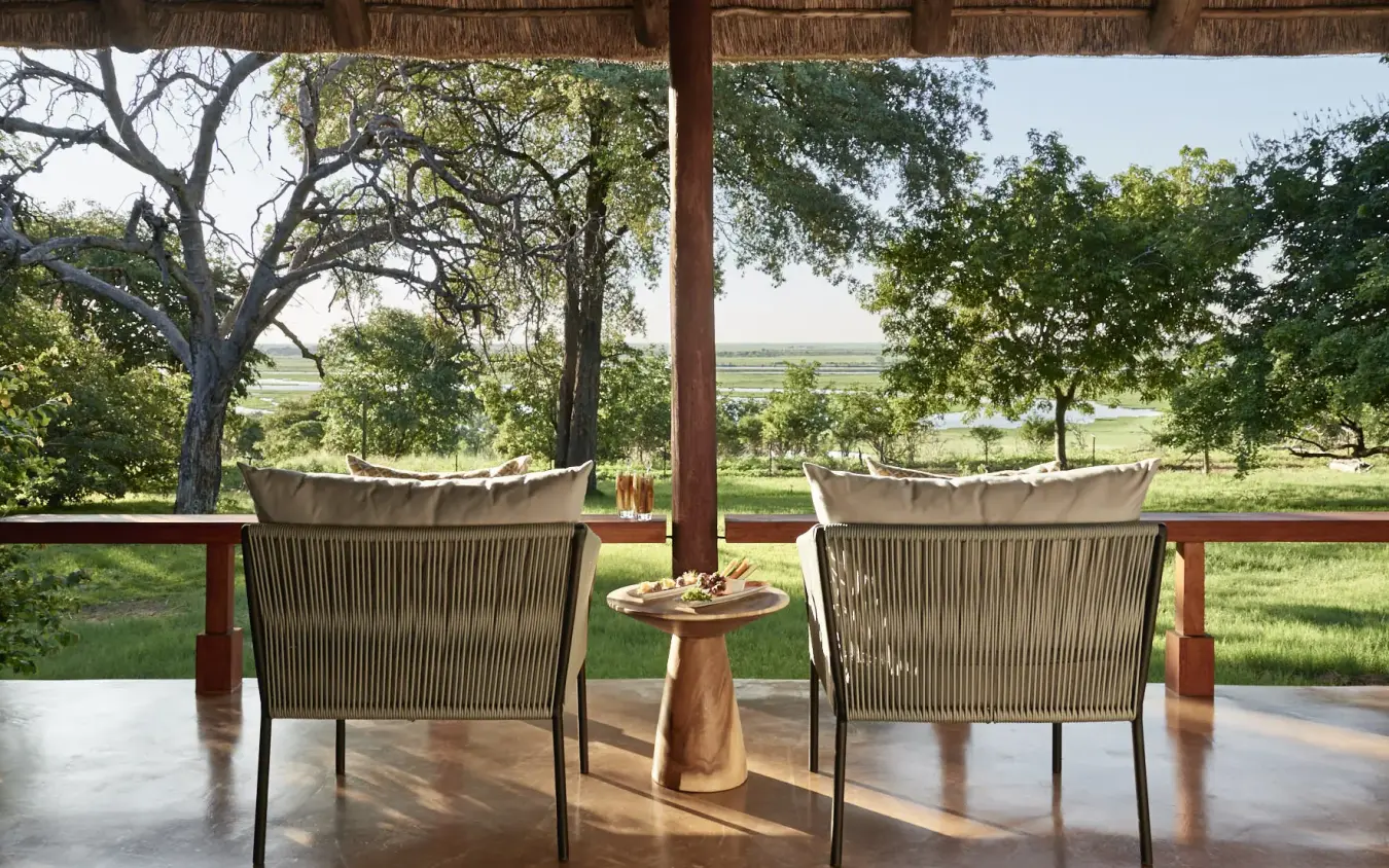 Two lounge chairs on covered terrace overlooking river valley landscape, Chobe Chilwero, Chobe, Botswana