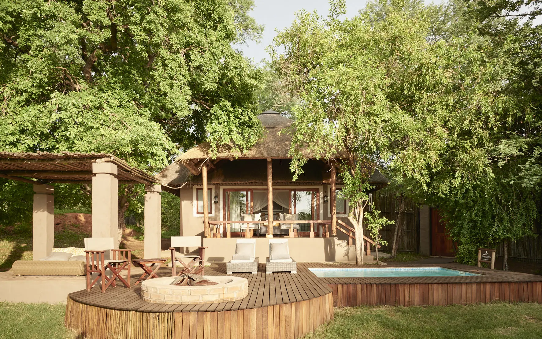 Wooden deck with seating area and pool overlooking lush forest canopy, Chobe Chilwero, Chobe, Botswana