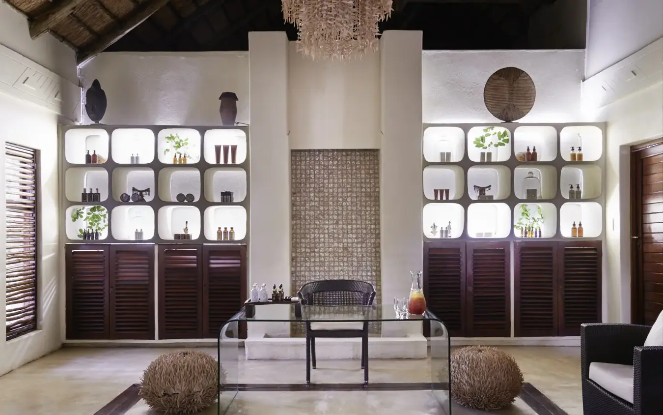Luxury spa interior with illuminated display shelving and central fireplace, Chobe Chilwero, Chobe, Botswana