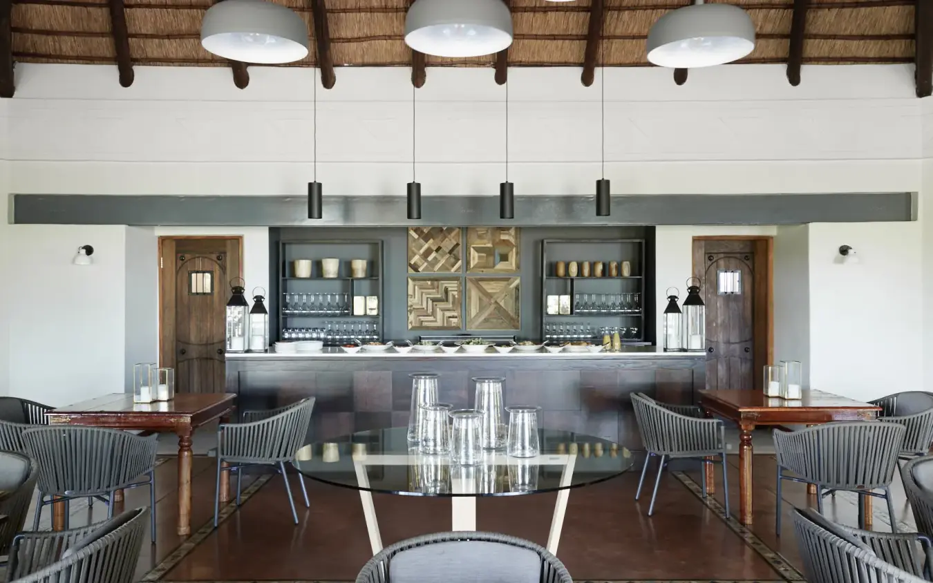 Modern lodge bar and dining area with thatched ceiling and geometric wall art, Chobe Chilwero, Chobe, Botswana