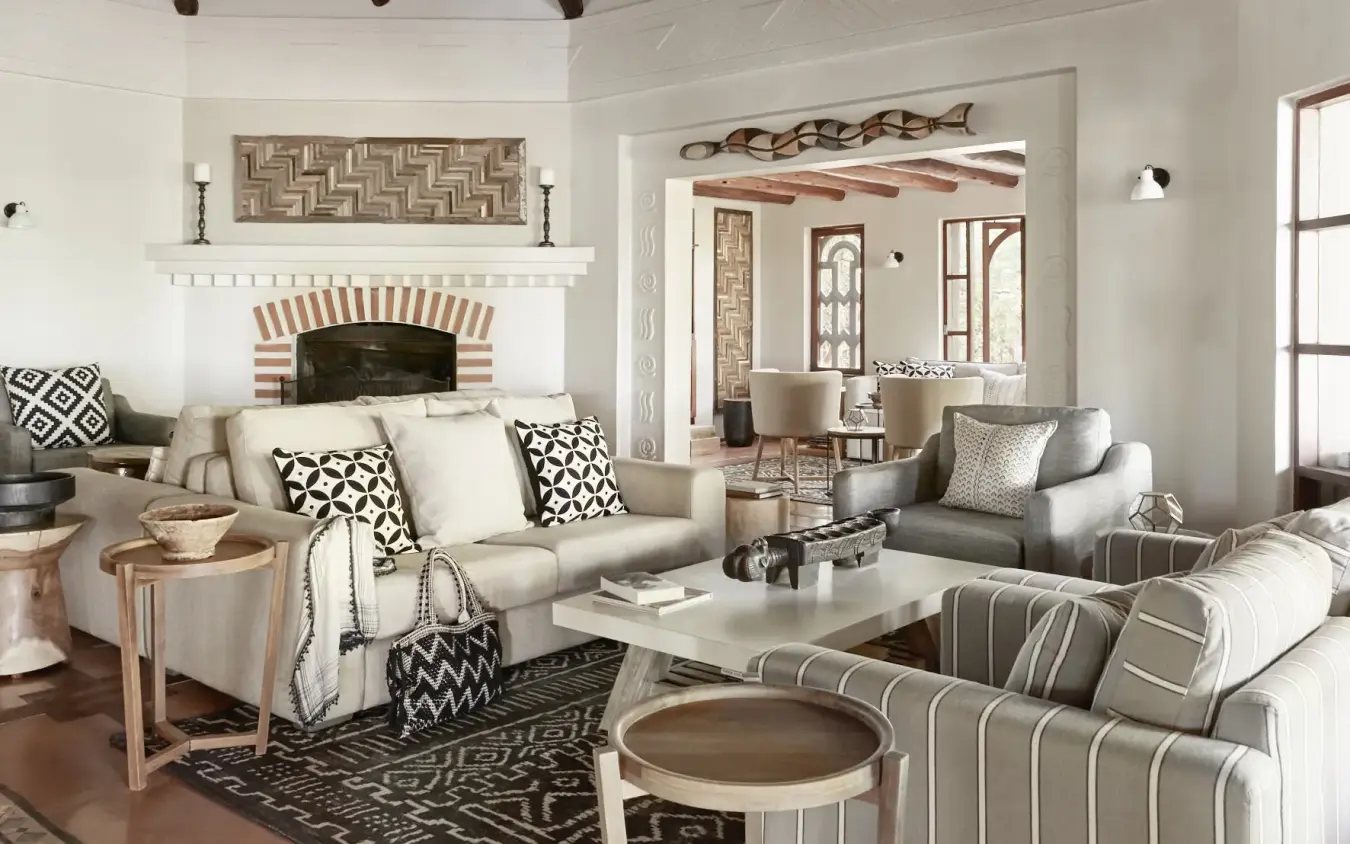 Luxury lodge interior with fireplace, neutral furnishings and geometric patterned textiles, Chobe Chilwero, Chobe, Botswana