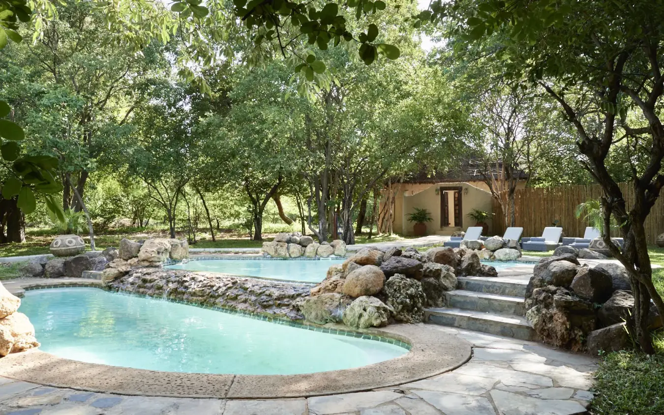 Luxury thermal pools with natural rock features nestled under mature trees, Chobe Chilwero, Chobe, Botswana