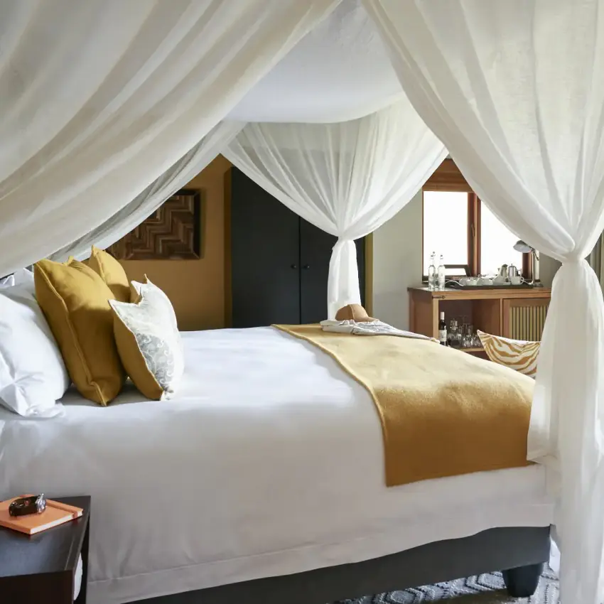 Luxury bedroom with four-poster bed and open terrace overlooking garden, Chobe Chilwero, Chobe, Botswana