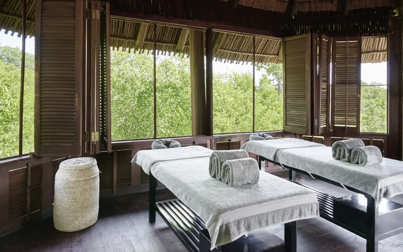 Spa treatment room with twin beds overlooking dense green forest canopy, Chobe Chilwero, Chobe, Botswana