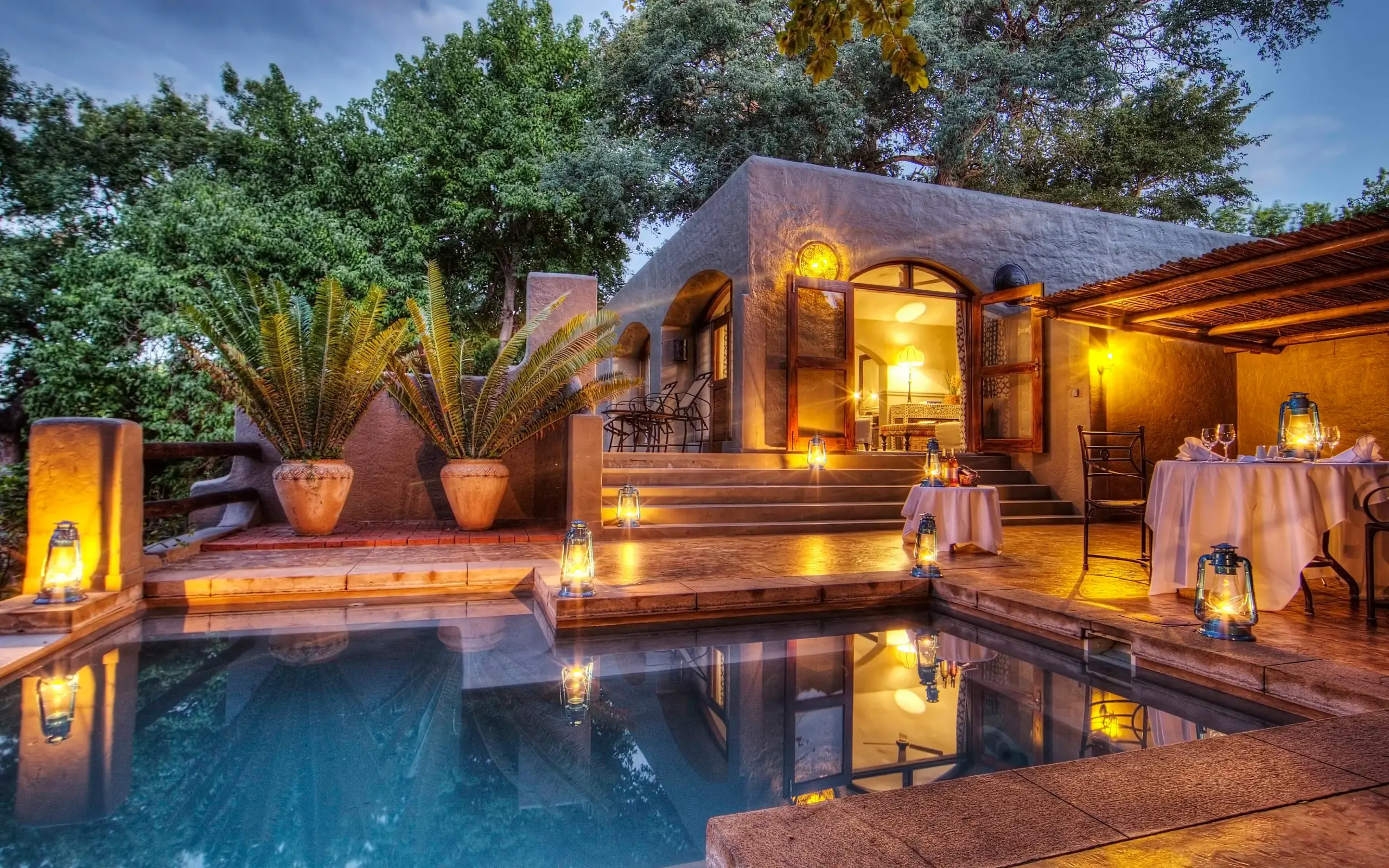 Illuminated lodge with pool reflecting evening lights and surrounding vegetation, Chobe Game Lodge, Chobe, Botswana
