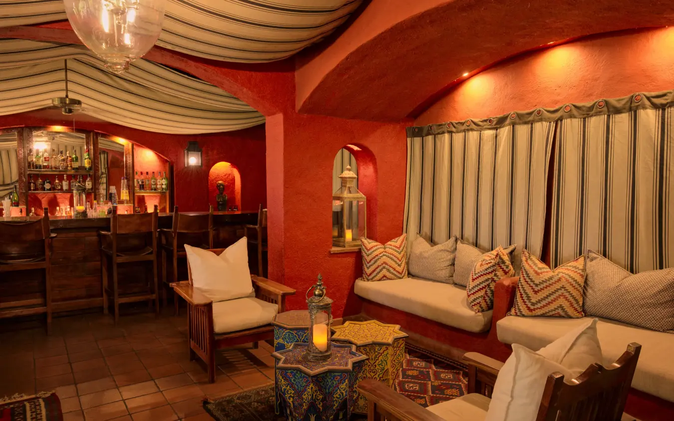 Luxury lounge interior with red walls, bar counter, and cushioned seating area, Chobe Game Lodge, Chobe, Botswana