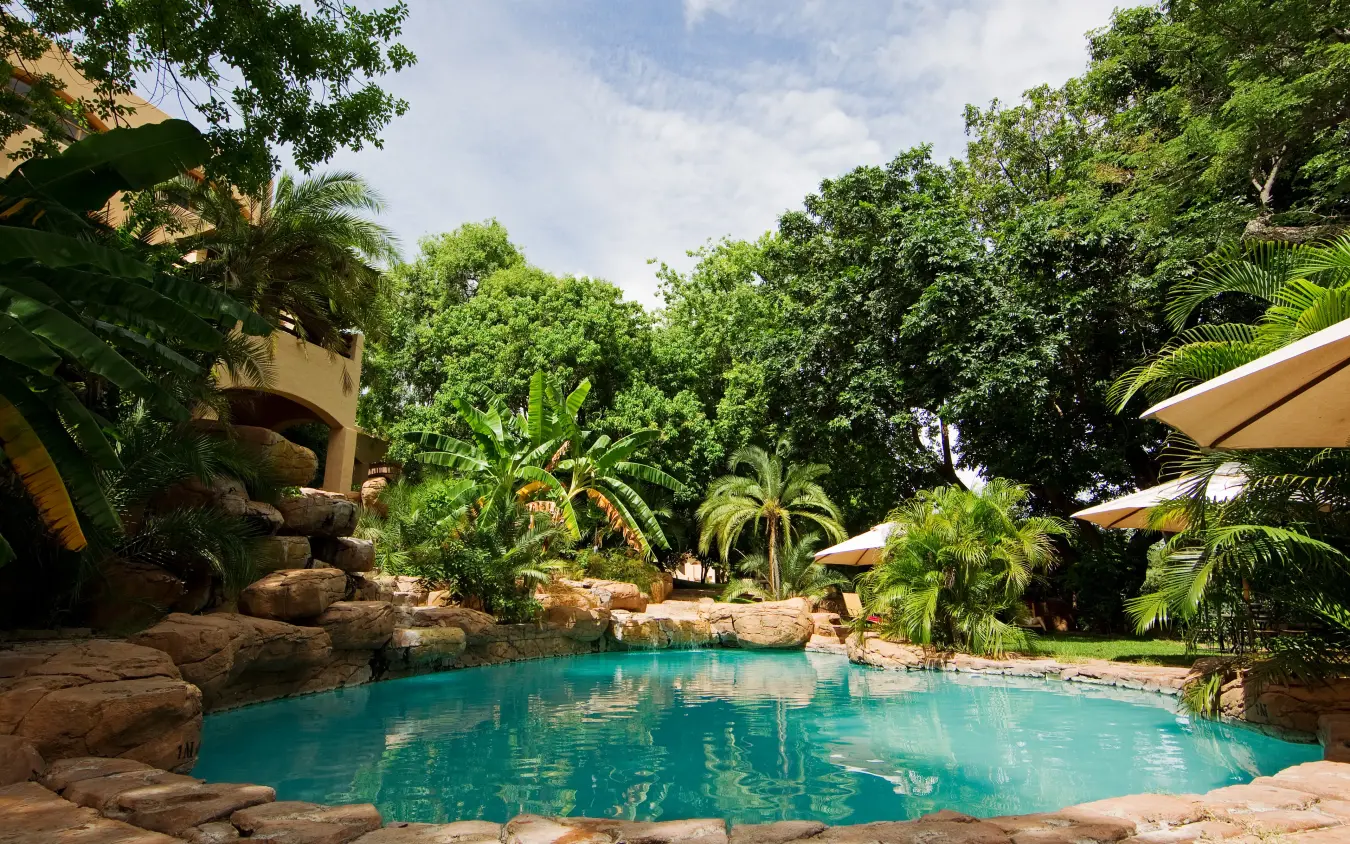 Luxury pool with natural rock features surrounded by lush tropical gardens, Chobe Game Lodge, Chobe, Botswana