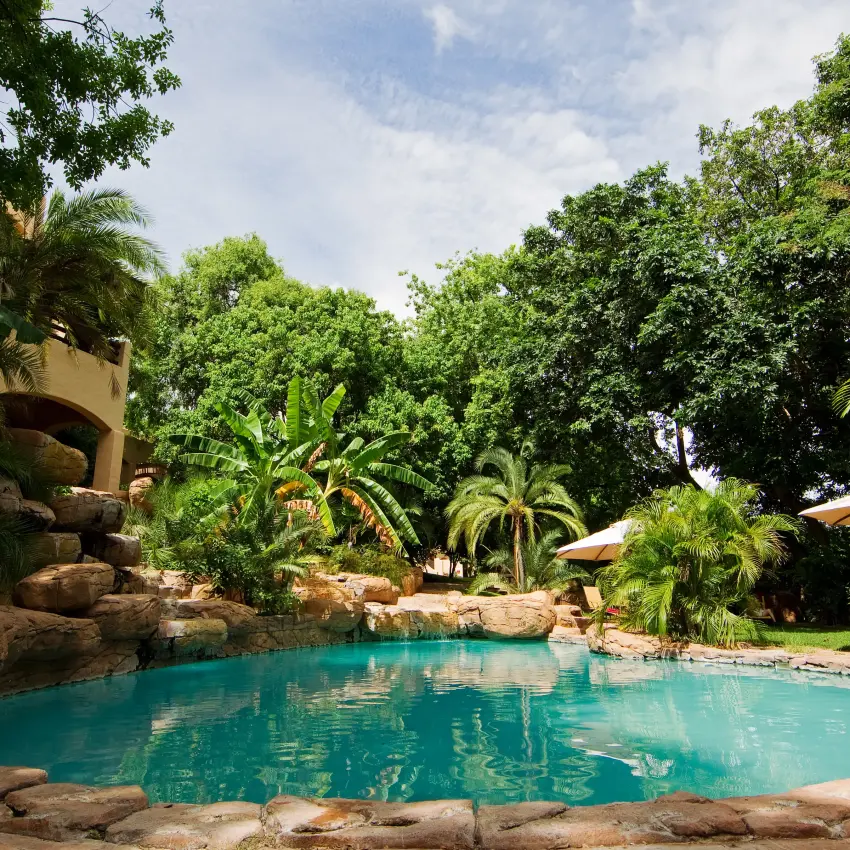 Luxury pool with natural rock features surrounded by lush tropical gardens, Chobe Game Lodge, Chobe, Botswana