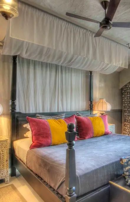 Four-poster bed with colorful striped cushions in luxury bedroom interior, Chobe Game Lodge, Chobe, Botswana