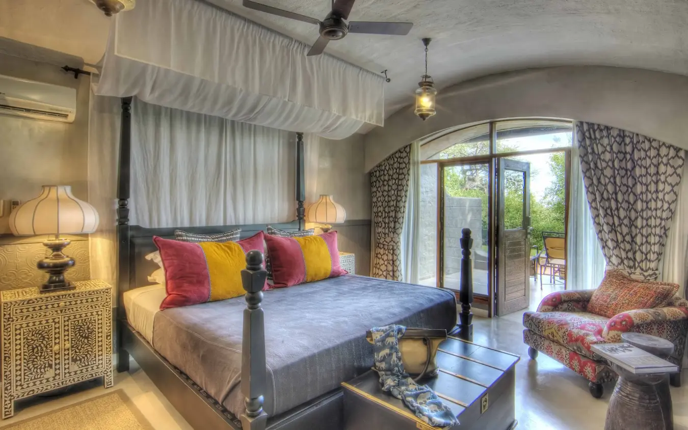 Luxury bedroom suite with four-poster bed and arched windows overlooking garden, Chobe Game Lodge, Chobe, Botswana