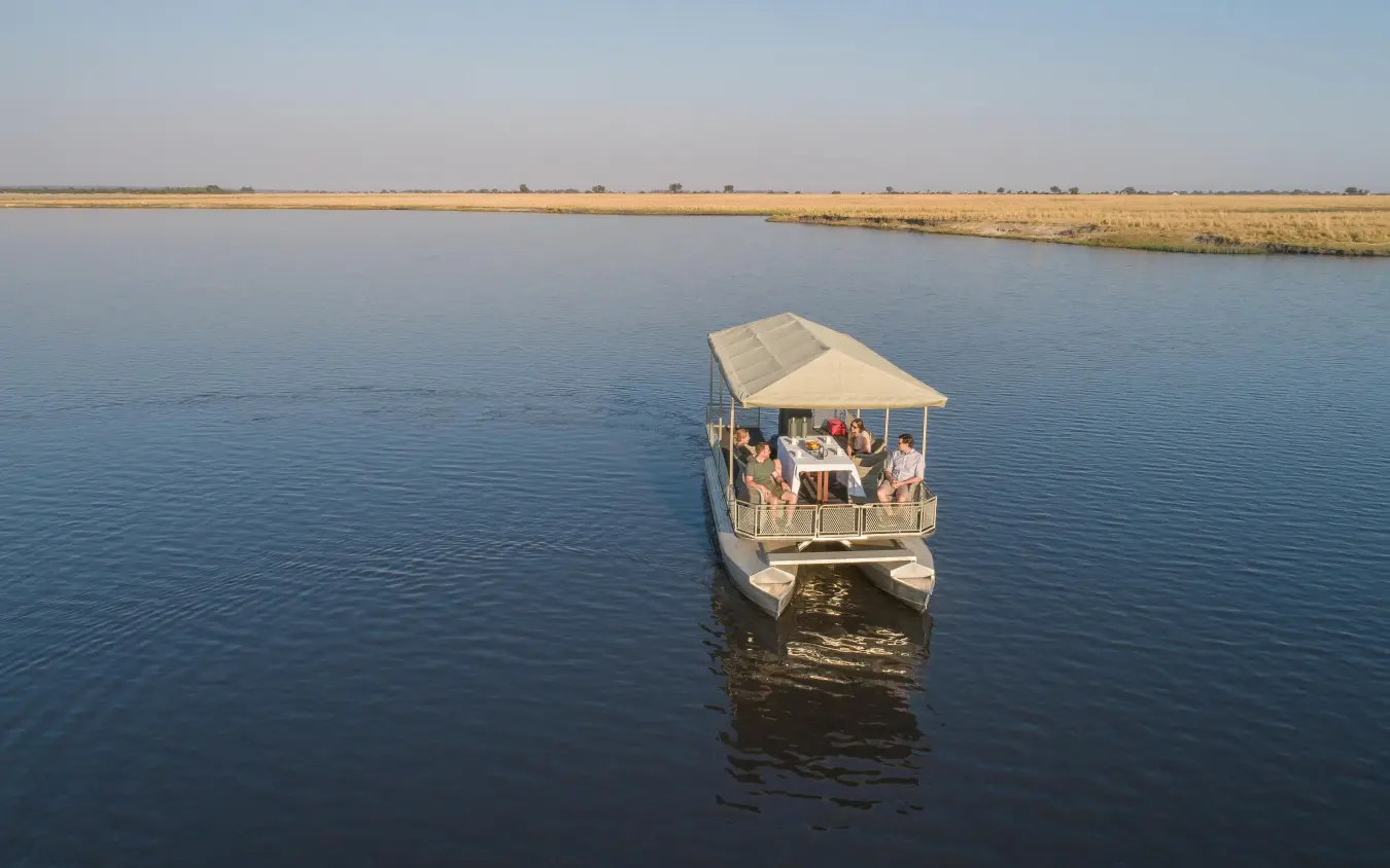 Boat with canopy carrying guests on calm waterway, Chobe Savanna Lodge, Zambezi Region, Namibia