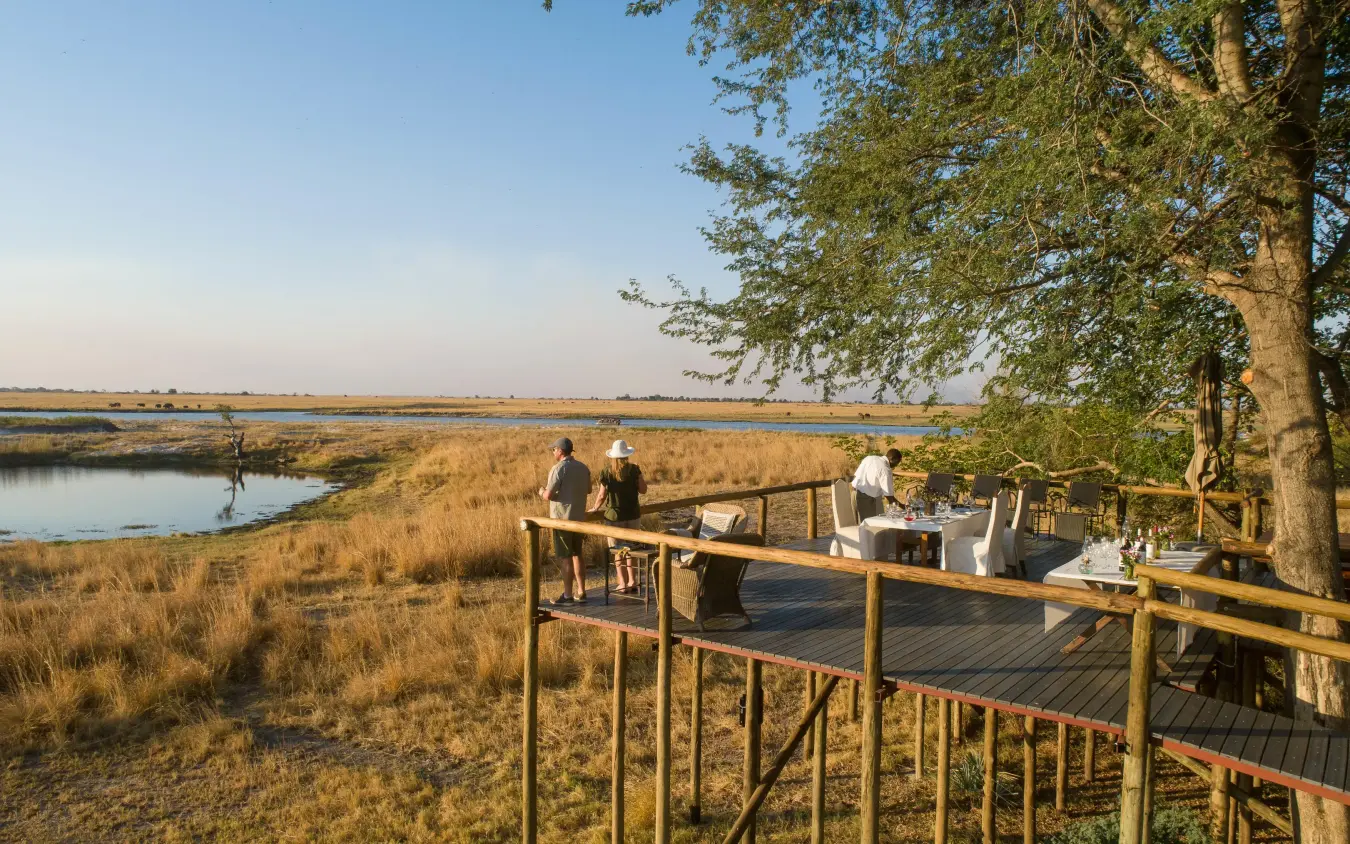 Wooden deck overlooking wetland with guests dining, Chobe Savanna Lodge, Zambezi Region, Namibia