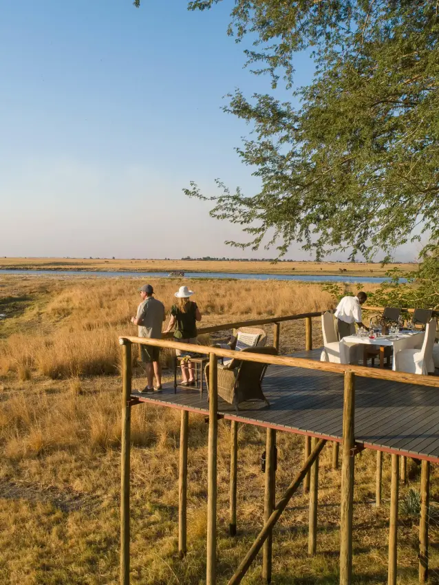Wooden deck overlooking wetland with guests dining, Chobe Savanna Lodge, Zambezi Region, Namibia