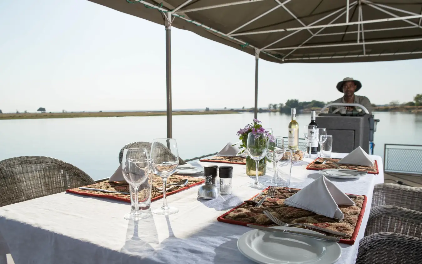 Waterfront dining table set with place settings and refreshments, Chobe Savanna Lodge, Zambezi Region, Namibia
