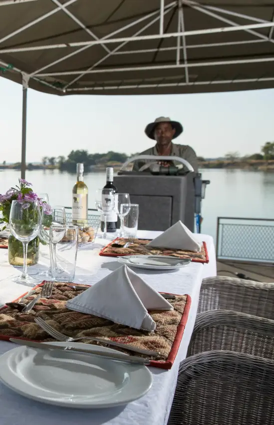 Waterfront dining table set with place settings and refreshments, Chobe Savanna Lodge, Zambezi Region, Namibia