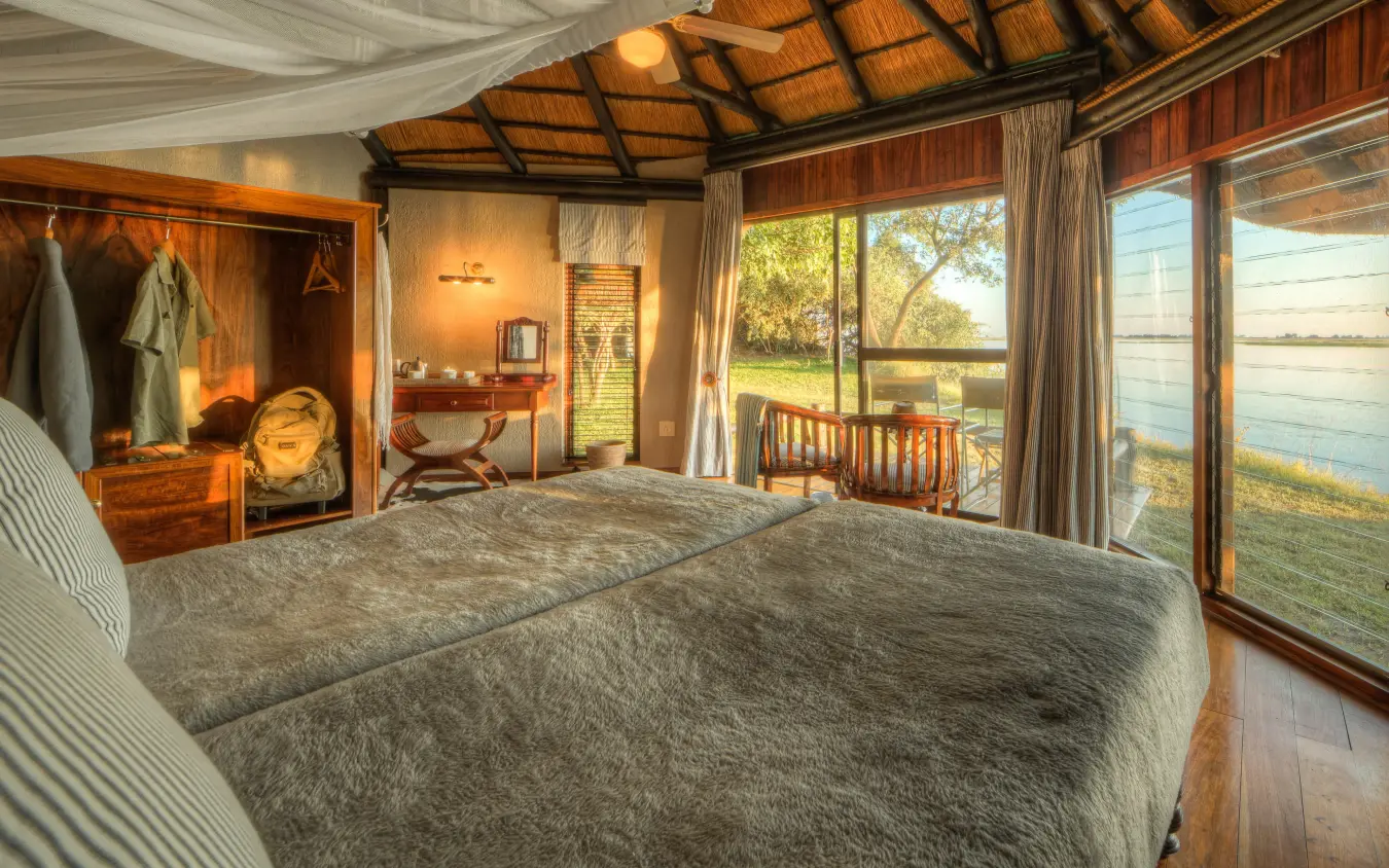 Bedroom with large windows overlooking river and grassland, Chobe Savanna Lodge, Zambezi Region, Namibia