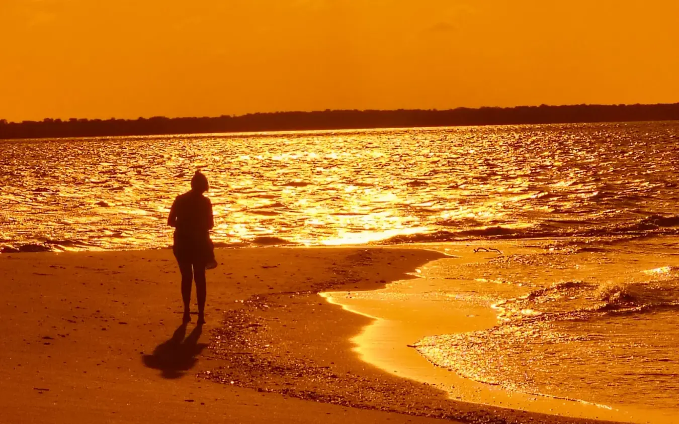 Silhouetted figure standing on beach at golden sunset, Chuchungi House, Lamu Archipelago, Kenya