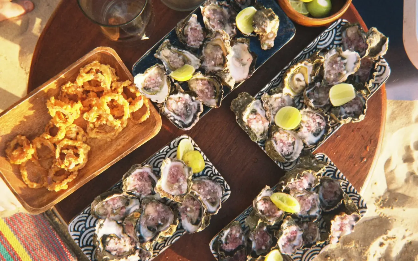 Oysters and grilled prawns served on wooden table outdoors, Chuchungi House, Lamu Archipelago, Kenya