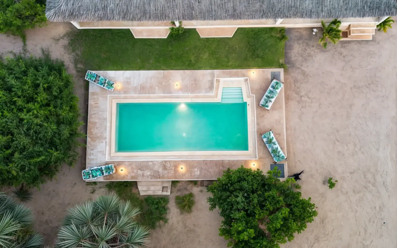 Aerial view of rectangular swimming pool with loungers on sandy grounds surrounded by vegetation, Chuchungi House, Lamu Archipelago, Kenya