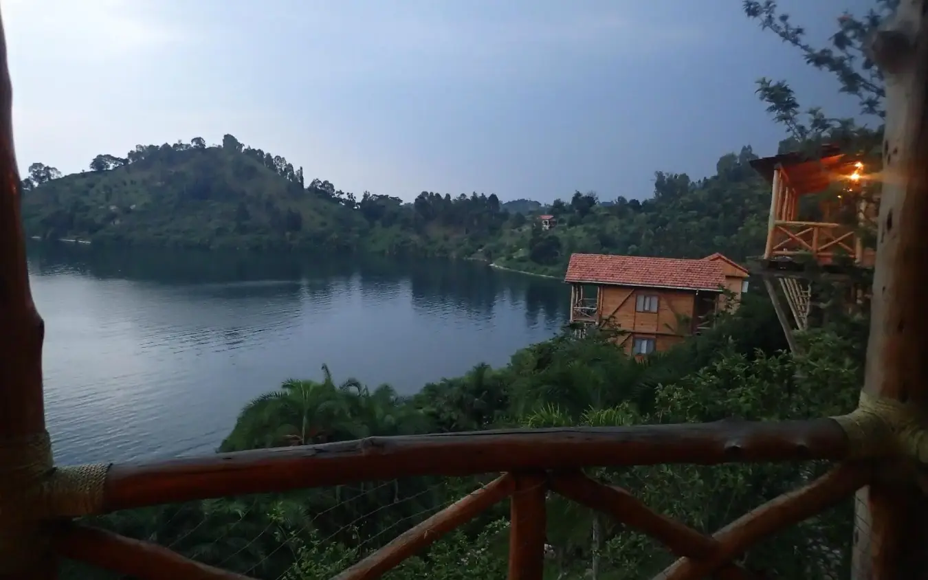 Riverside lodge with wooden deck overlooking forested river valley at dusk, Cormoran Lodge, Lake Kivu, Rwanda