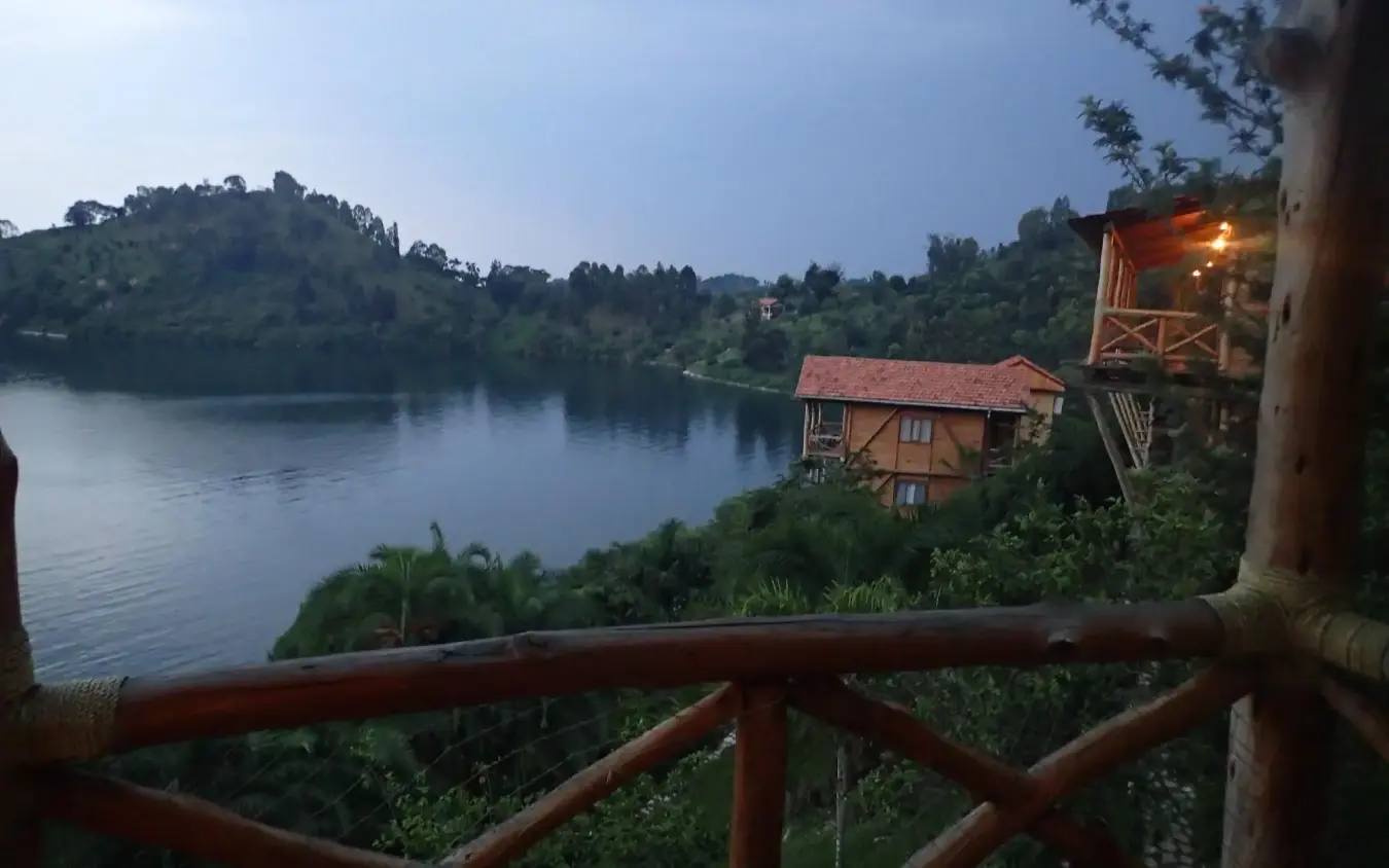 Wooden deck overlooking river with forested hills and lodge building at dusk, Cormoran Lodge, Lake Kivu, Rwanda