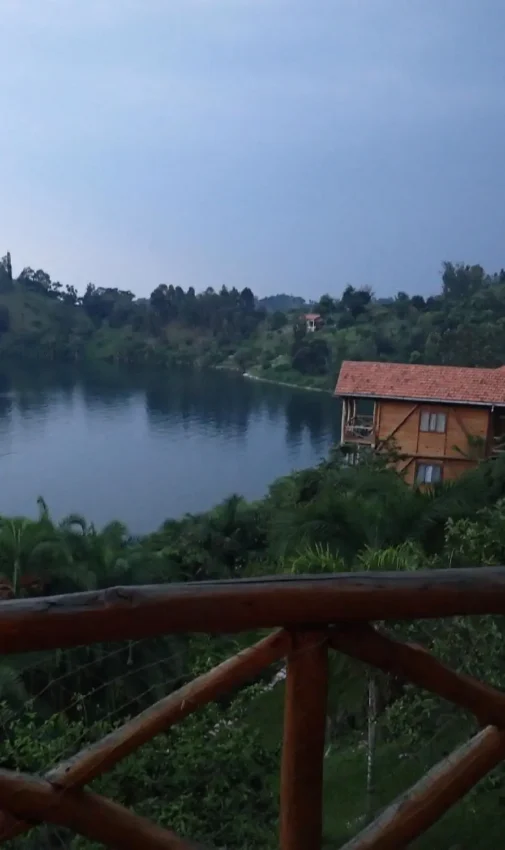 Wooden deck overlooking river with forested hills and lodge building at dusk, Cormoran Lodge, Lake Kivu, Rwanda