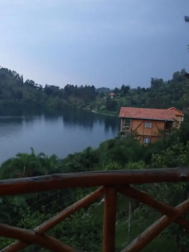 Wooden deck overlooking river with forested hills and lodge building at dusk, Cormoran Lodge, Lake Kivu, Rwanda