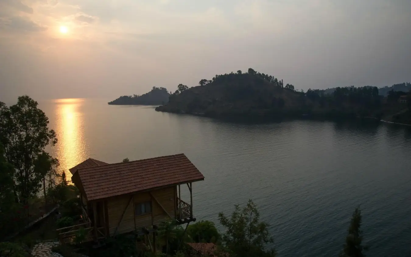 Lakeside cottage with red roof at sunset overlooking forested peninsula, Cormoran Lodge, Lake Kivu, Rwanda