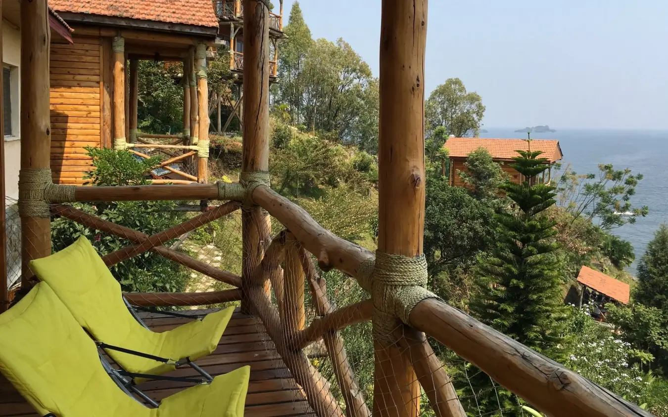 Treehouse deck with hammocks overlooking forested coastline and ocean horizon, Cormoran Lodge, Lake Kivu, Rwanda