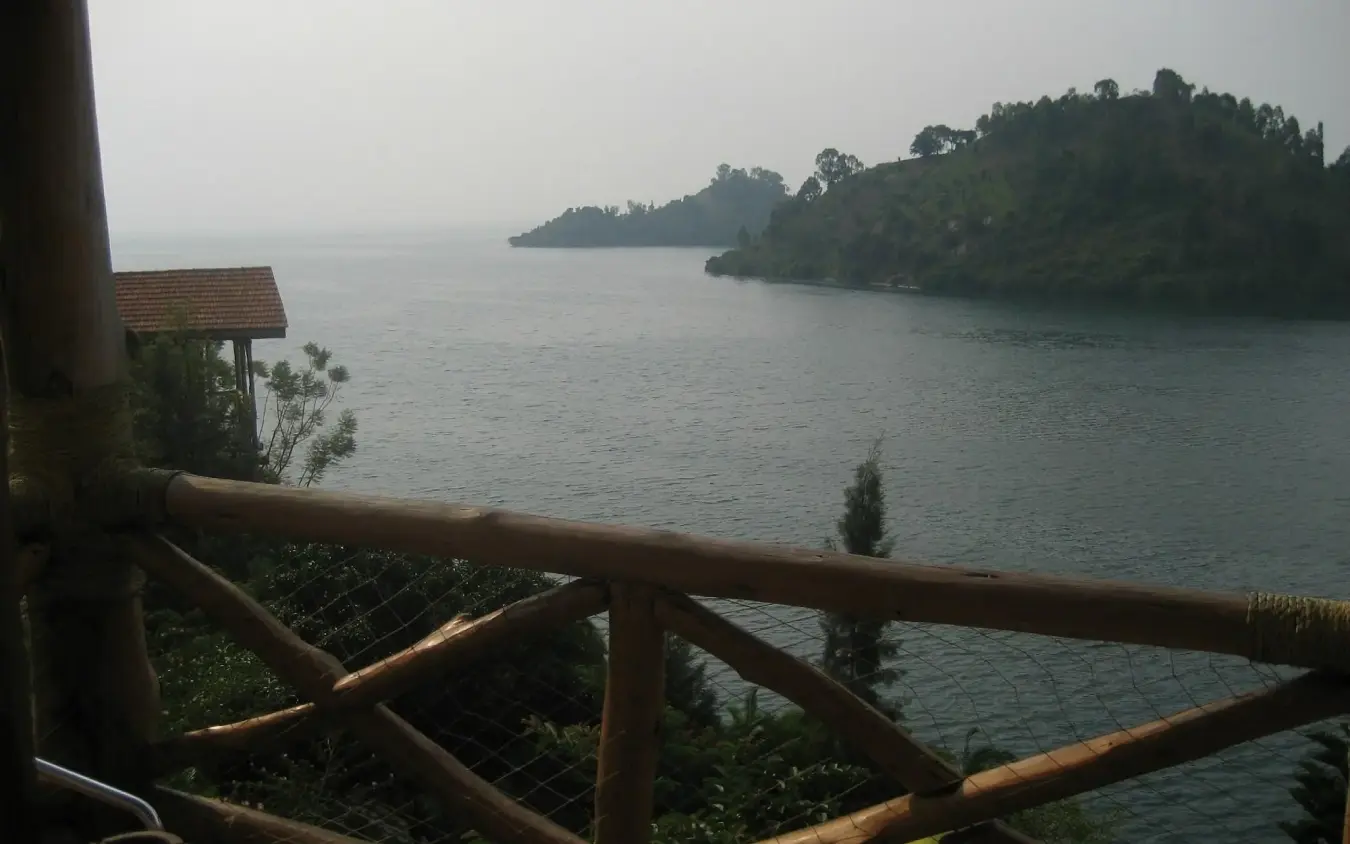 Wooden deck railing overlooking forested peninsula and calm water, Cormoran Lodge, Lake Kivu, Rwanda