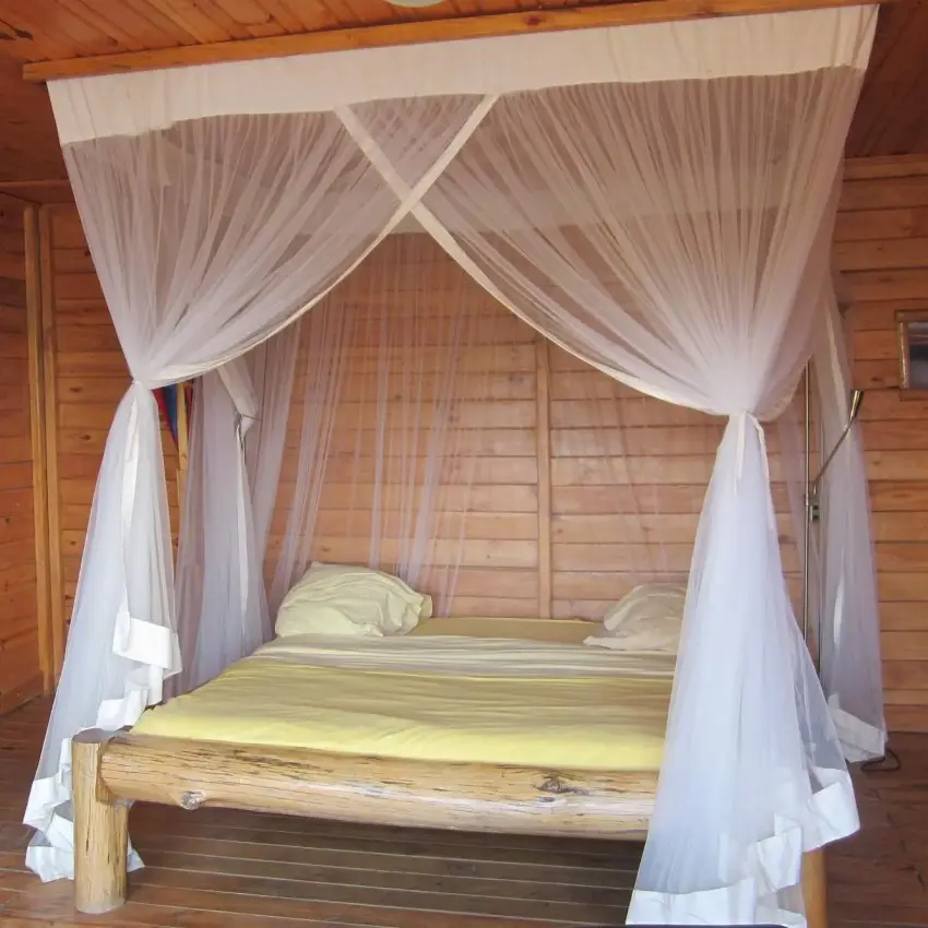 Four-poster bed with sheer drapes in wooden lodge bedroom, Cormoran Lodge, Lake Kivu, Rwanda