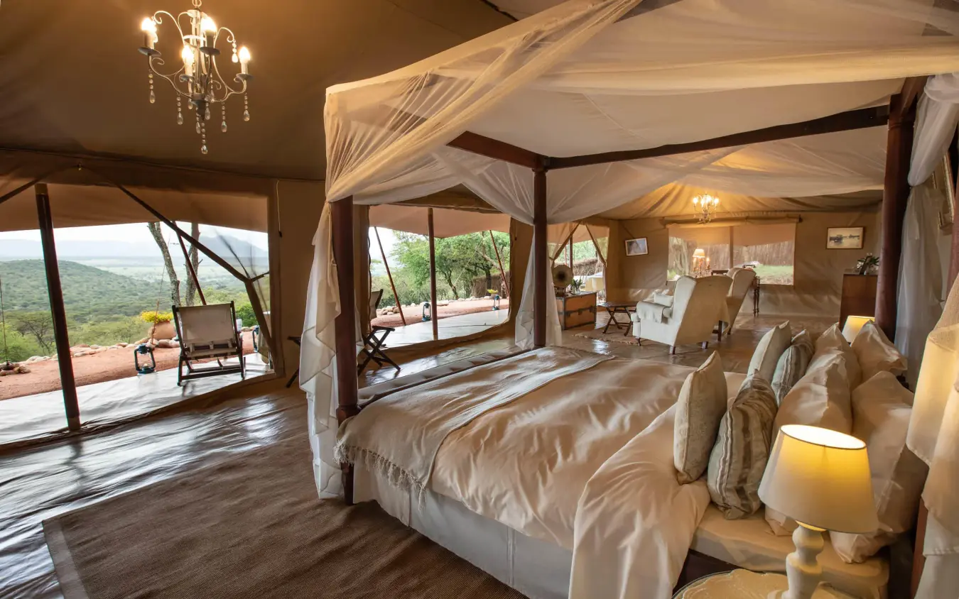 Spacious safari tent bedroom with four-poster bed and valley views, Cottar’s 1920s Camp, Maasai Mara, Kenya