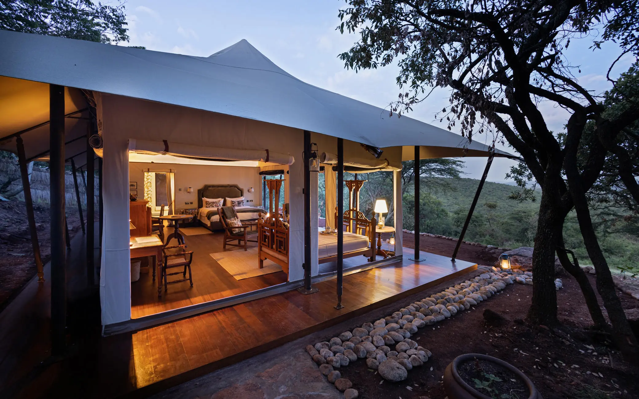 Canvas tent accommodation glowing at dusk with veranda, Cottar’s 1920s Camp, Maasai Mara, Kenya