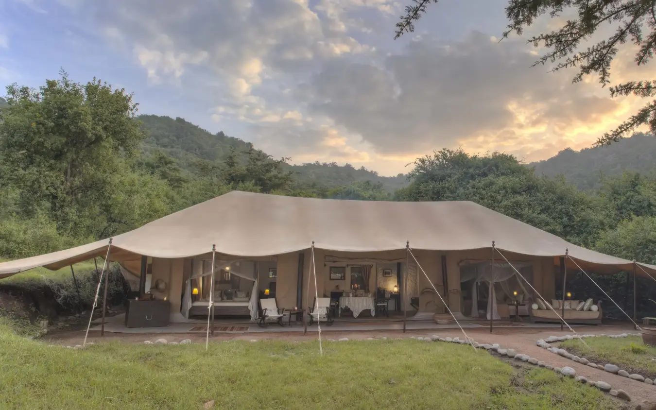 Canvas safari lodge tent nestled in wooded valley at dusk, Cottar’s 1920s Camp, Maasai Mara, Kenya