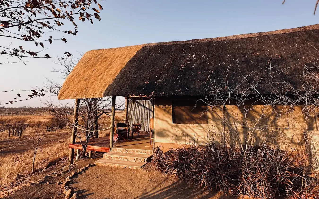 Thatched-roof safari lodge with wooden veranda overlooking dry savanna landscape, Daka Plains Camp, Hwange National Park, Zimbabwe