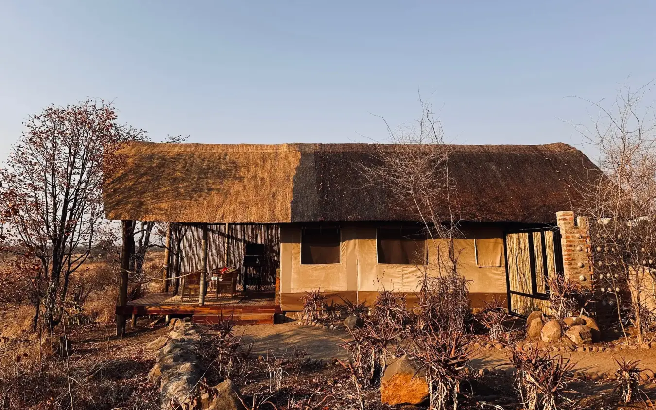 Thatched-roof safari lodge with wooden deck overlooking dry savanna landscape, Daka Plains Camp, Hwange National Park, Zimbabwe